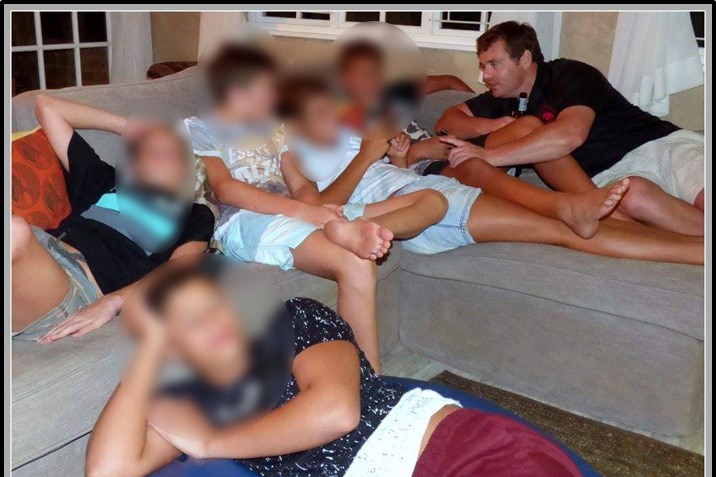young boys on a couch with faces blurred, man sitting amongst them