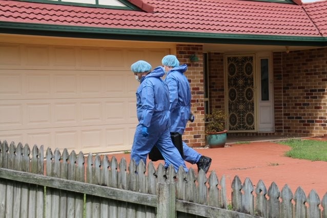Two people in blue suits enter a home.