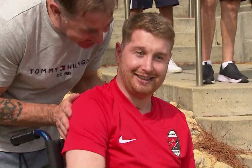 Danny Hodgson sits in his wheelchair smiling.