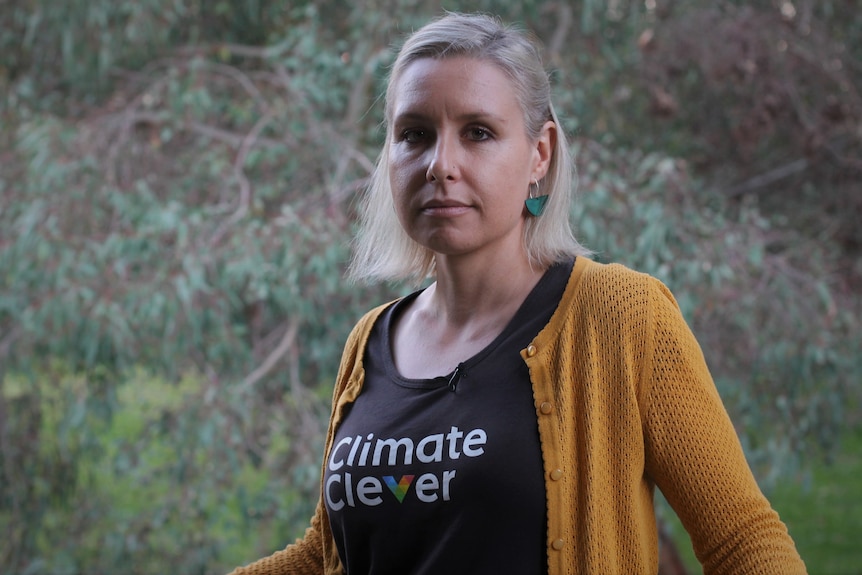 A close up of Vanessa wearing a black tshirt and yellow cardigan, looking into the camera.