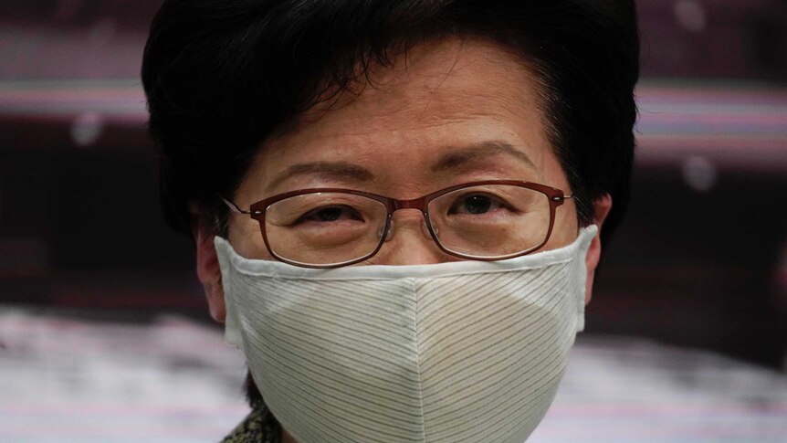 Hong Kong Chief Executive Carrie Lam wears a mask and looks at the camera.