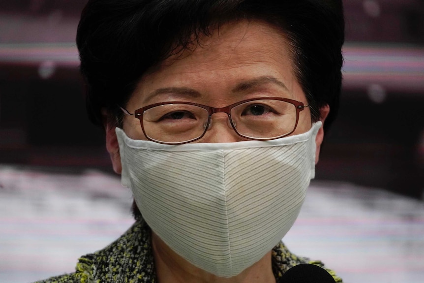 Hong Kong Chief Executive Carrie Lam wears a mask and looks at the camera.