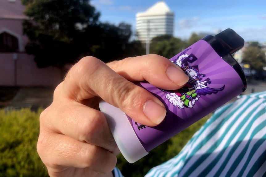 A hand holding a purple vape, Bunbury tower in the background