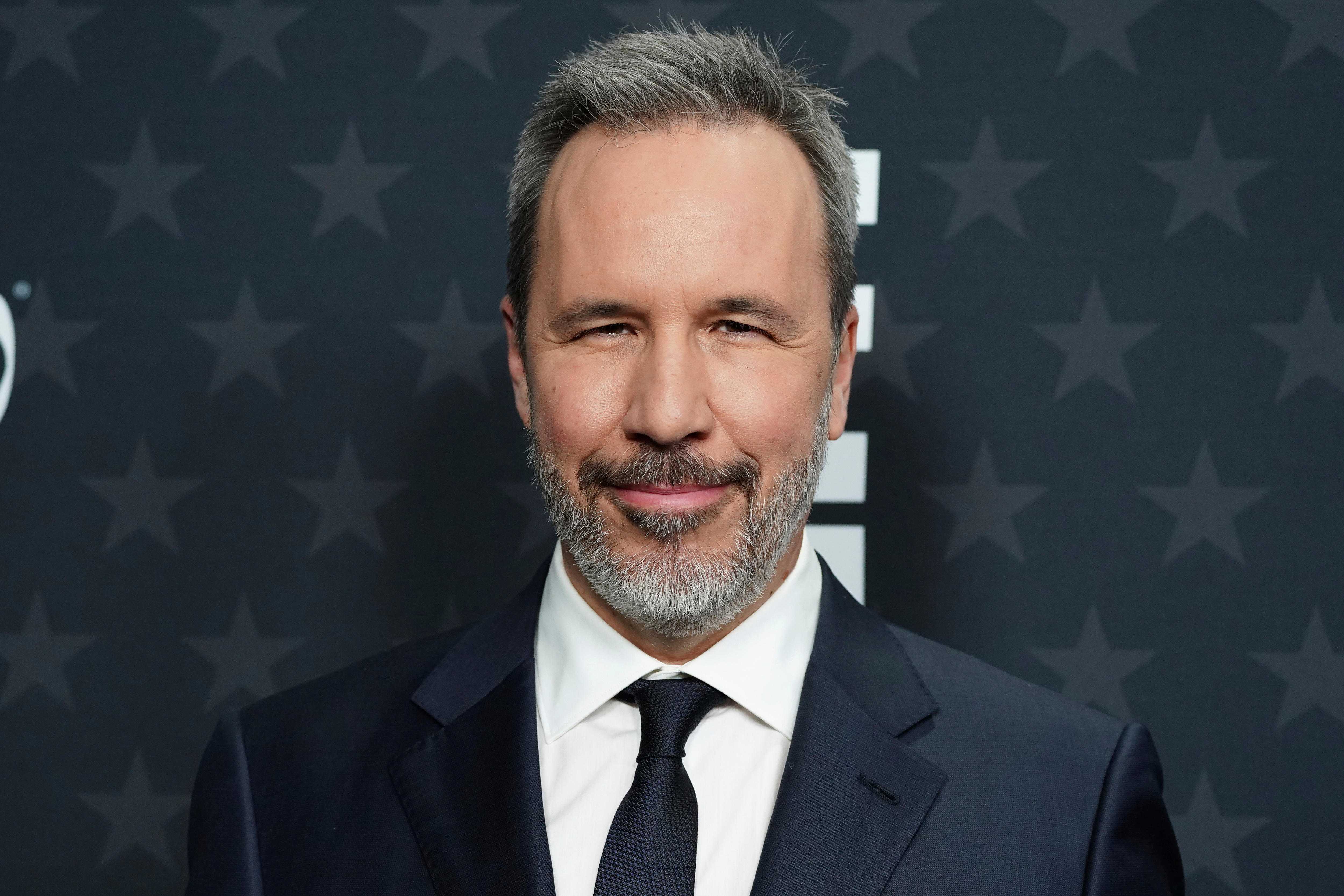 A middle-aged wearing a suit smiles