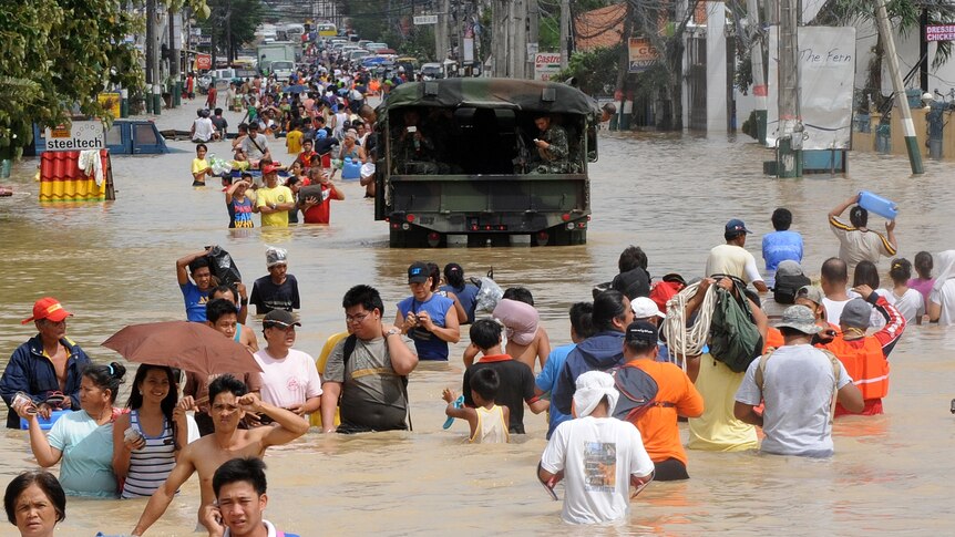 Residents wade through murky floodwaters in the aftermath of Typhoon Nalgae