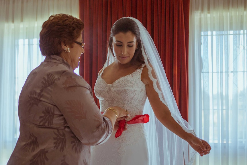Eleni's mother Soula performs a religious blessing ritual using a red ribbon.