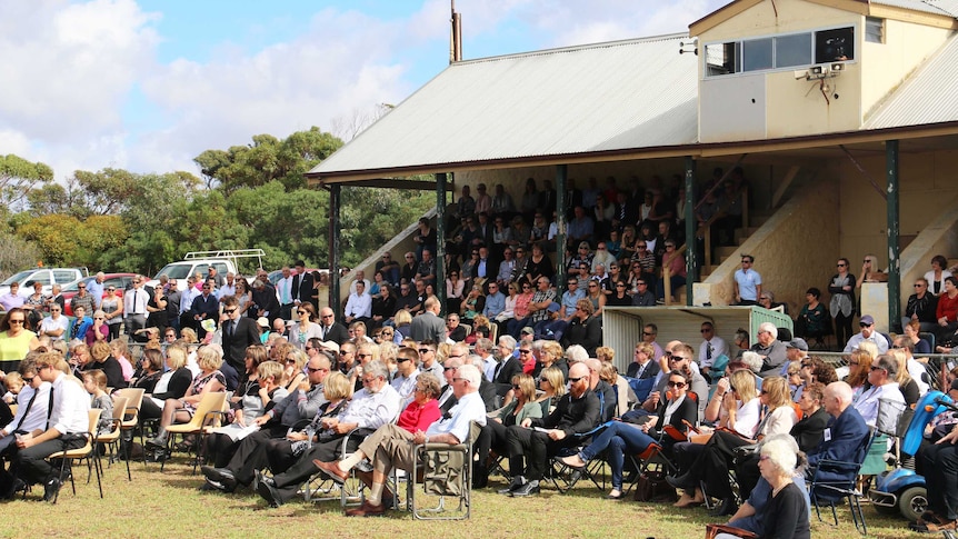 Mourners fill a grandstand.