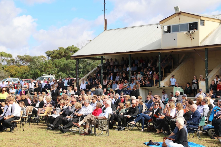 Mourners fill a grandstand.