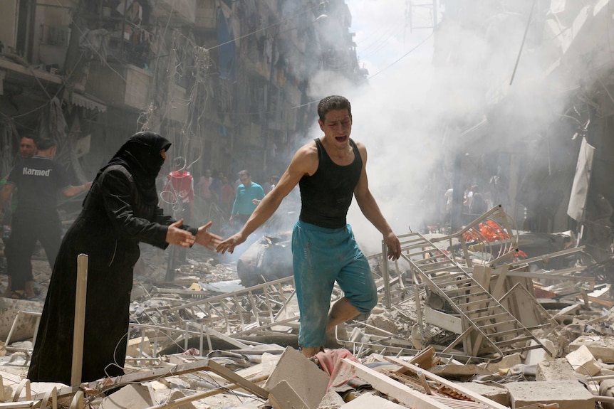 People walk amid the rubble of destroyed buildings following a reported air strike in Aleppo.