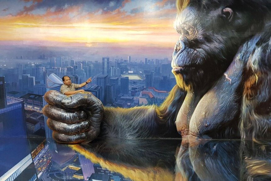 Sutopo Negroho poses in front of a large image of King Kong