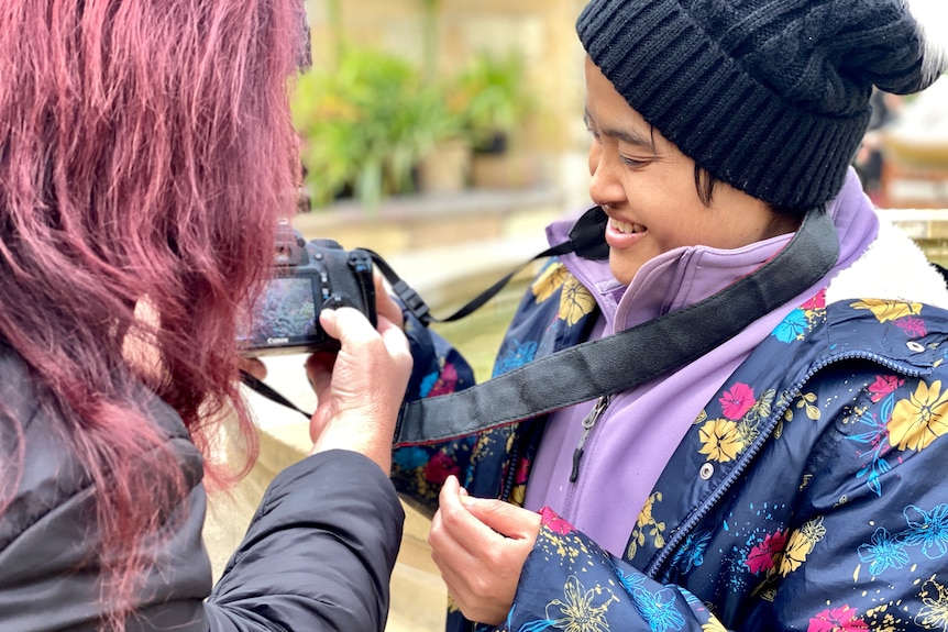 Two women check a viewfinder on a camera