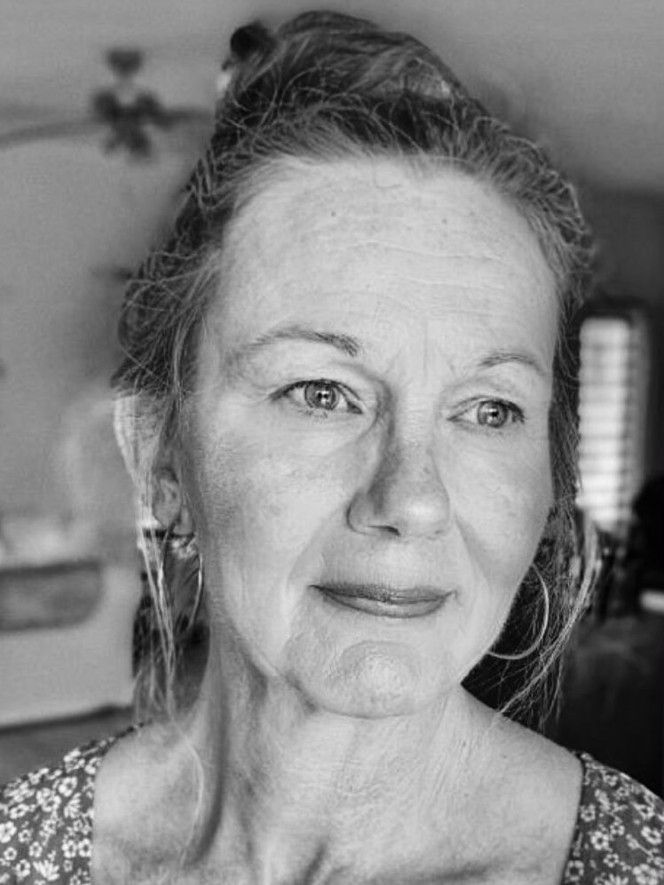 A close up black and white image of a woman's face with her hair tied up