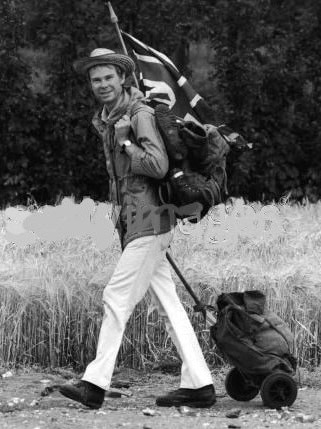 a black and white old photo of a man walking with a union jack flag