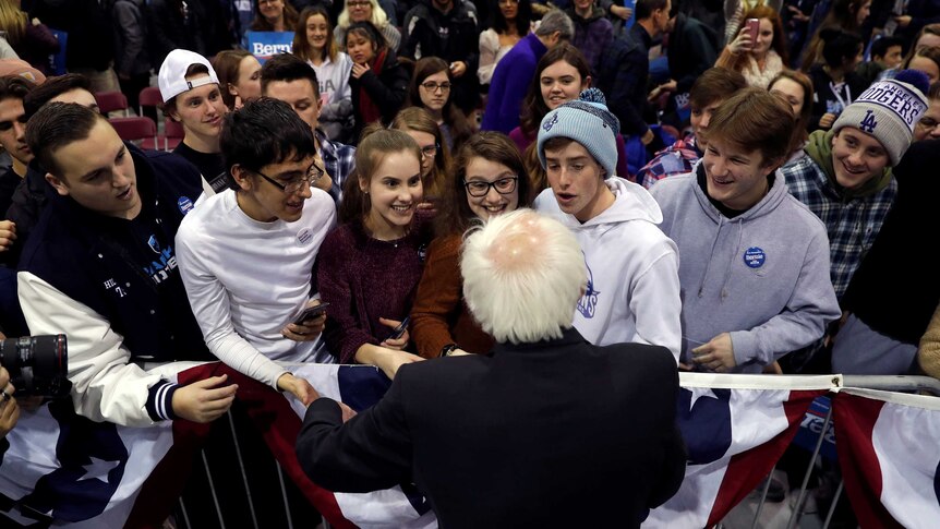 Bernie Sanders shaking hands with excited young voters