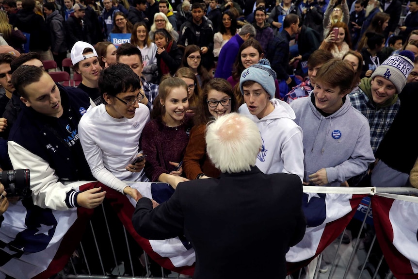 Bernie Sanders shaking hands with excited young voters