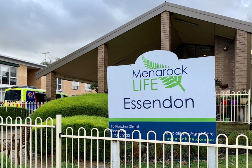 An ambulance is parked next to a brick building with a sign that reads Menarock Life Essendon out the front.