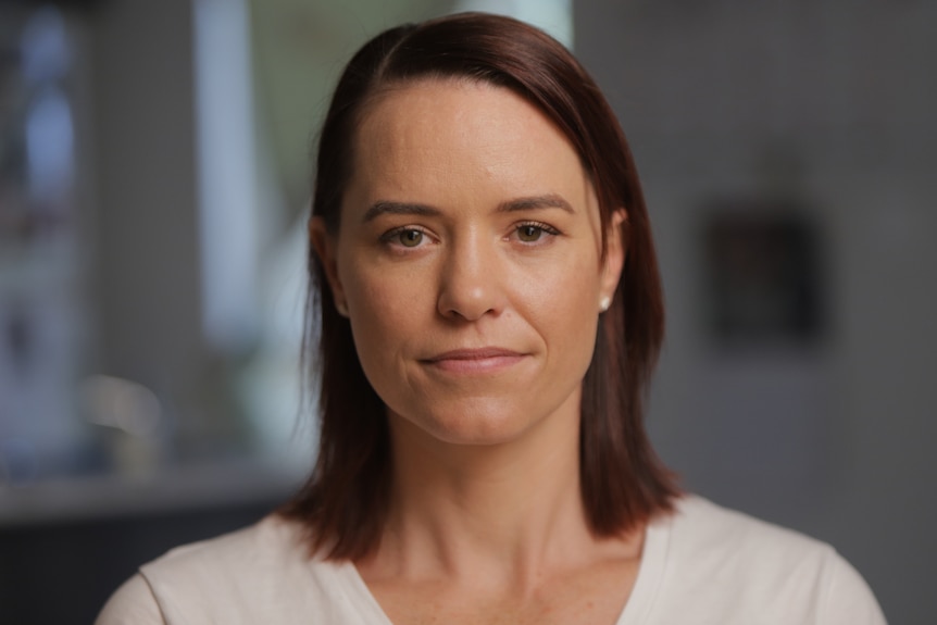 Woman wearing a white jumper with brown, shoulder-length hair. 