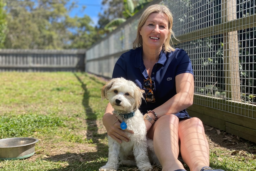 Woman sitting on ground beside a dog.