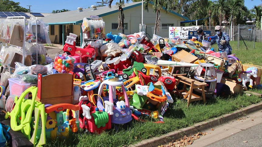RAAF personnel put flood-damaged toys onto a pile outside the Townsville Toy Library