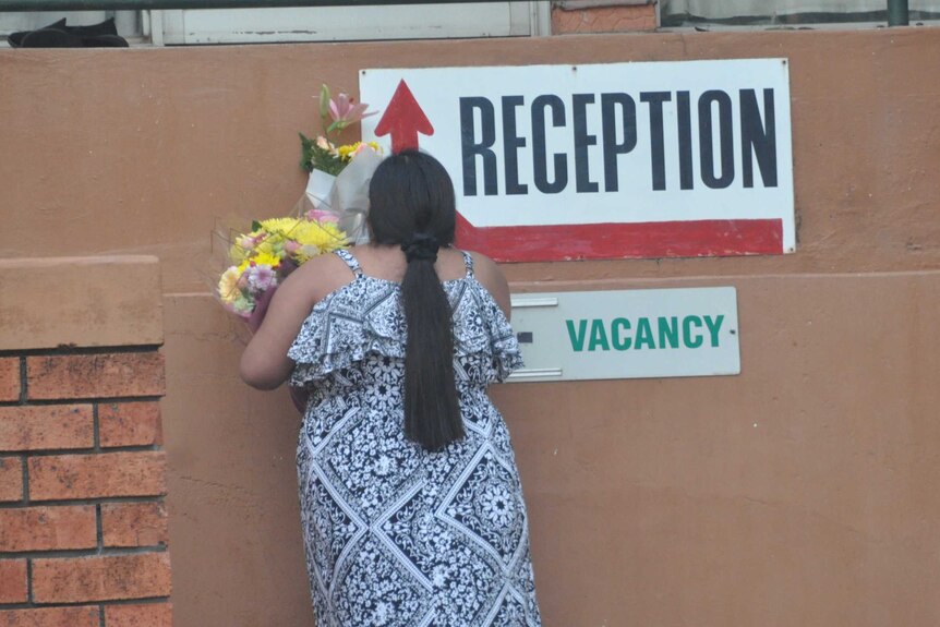 A mourner laying flowers at the Palms Motel in Darwin.