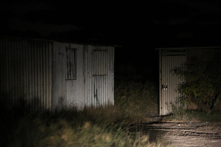 A picture of corrugated iron sheds pictured in the dark.