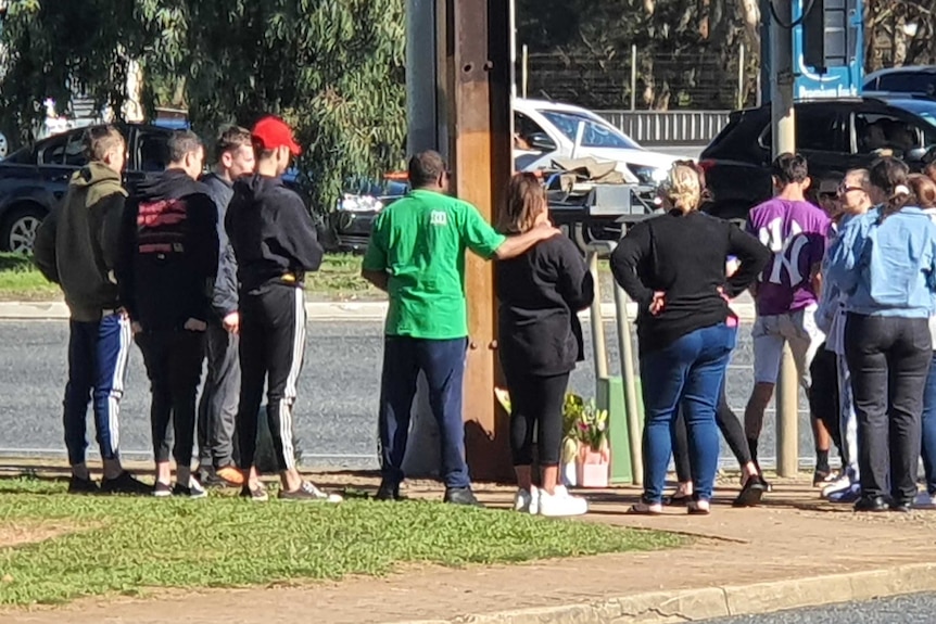 A group of people standing next to a stobie pole and a road