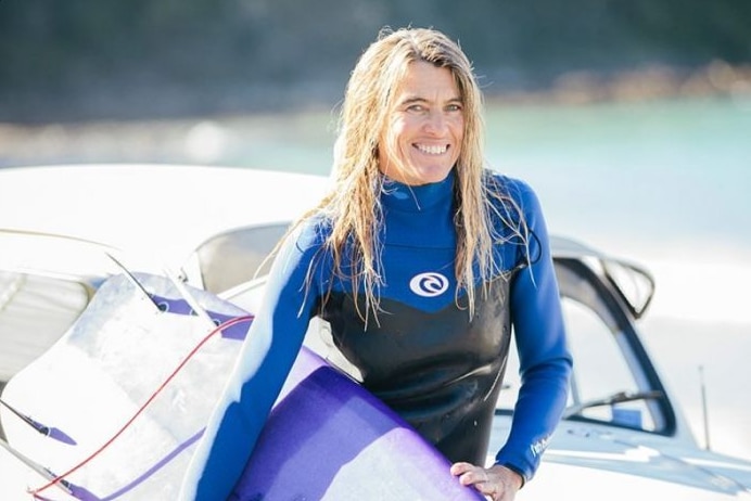 Australian surfing legend Pam Burridge holding a surfboard.