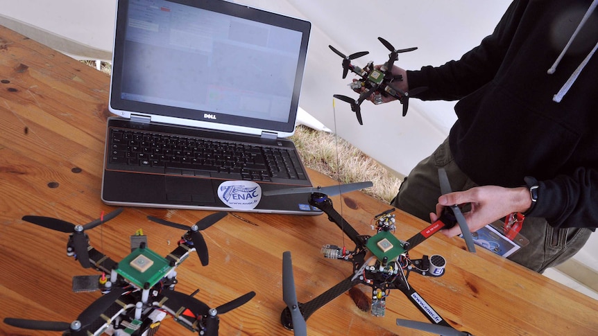 Small drones lined up next to laptop