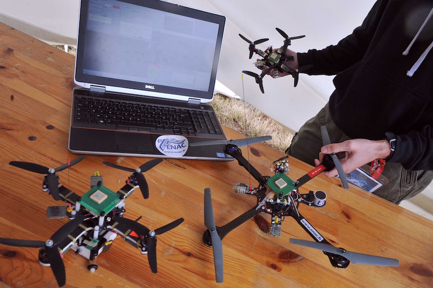 Small drones lined up next to laptop