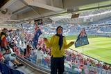 A woman holds Australian flags at a soccer match.