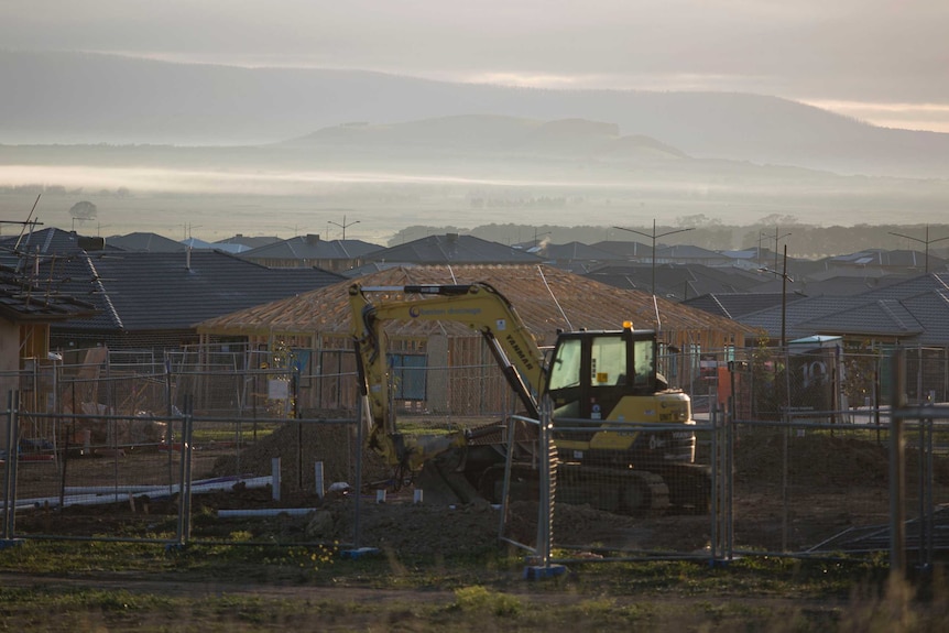 A digger on the construction site at a new housing estate in Mickleham, Victoria at sunrise.