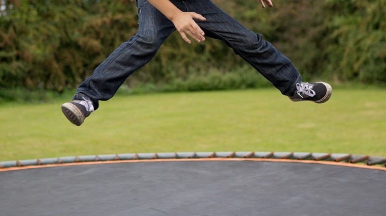 Unidentified boy jumping on trampoline.