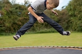 Unidentified boy jumping on trampoline.