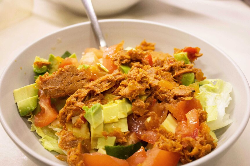 Tuna on salad in a bowl, a meal that's easy to fit into your meal preparation schedule and a good use of leftovers.
