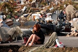 A young woman sits sobbing in the rubble of a destroyed village after an earthquake