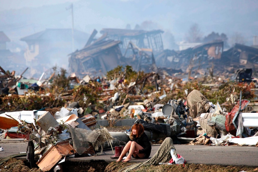 A young woman sits sobbing in the rubble of a destroyed village after an earthquake