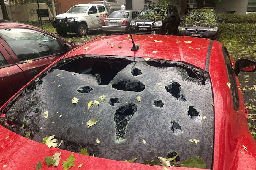 A red car with multiple holes in its rear windscreen