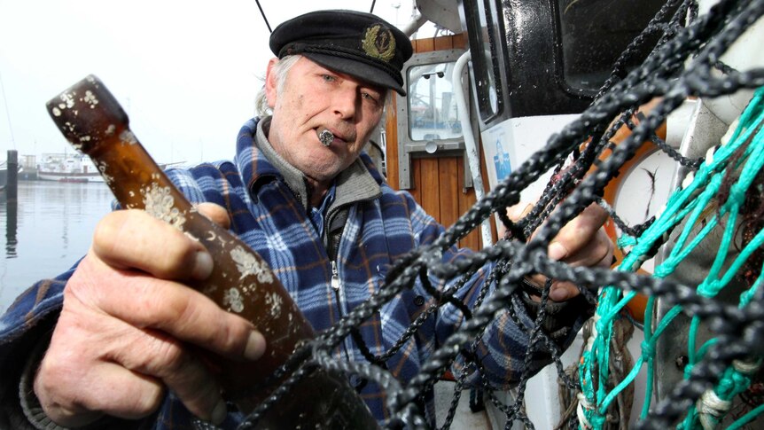 Fisherman Konrad Fischer holds a bottle containing a message from 1913.