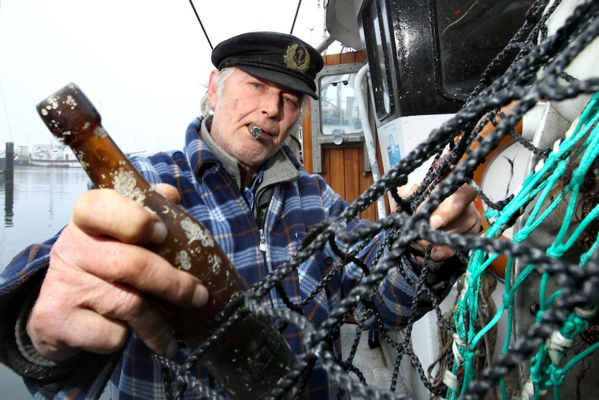 Fisherman Konrad Fischer holds a bottle containing a message from 1913.