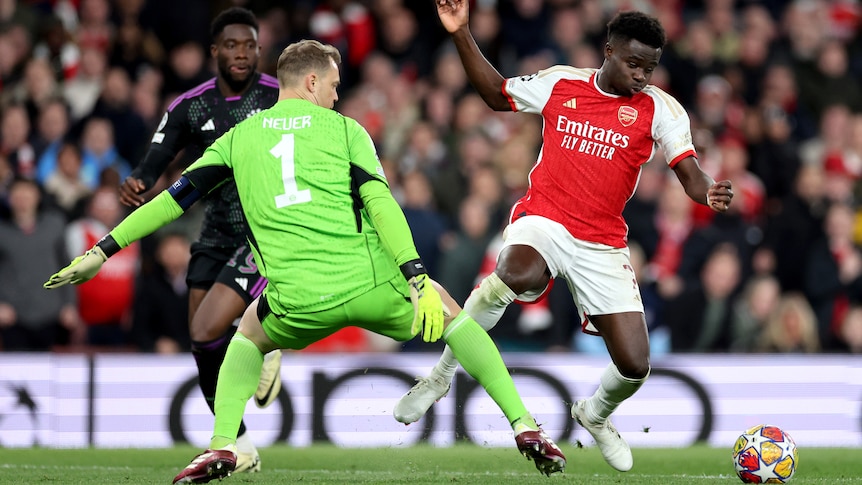 Arsenal's Bukayo Saka clashes legs with Bayern Munich goalkeeper Manuel Neuer during a Champions League game.