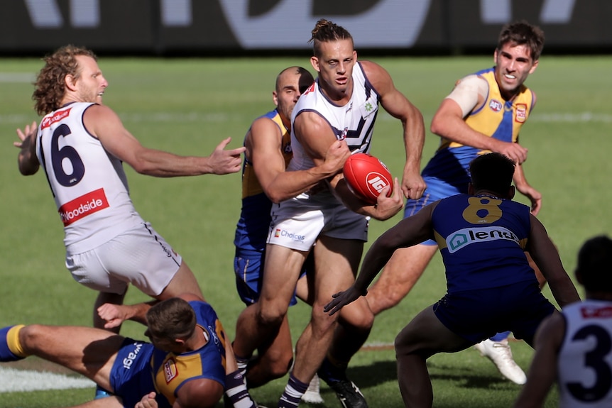 Nat Fyfe handballing while surrounded by Eagles and Dockers players