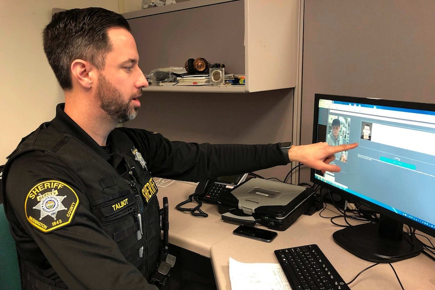 A police officer points at a face on a computer monitor