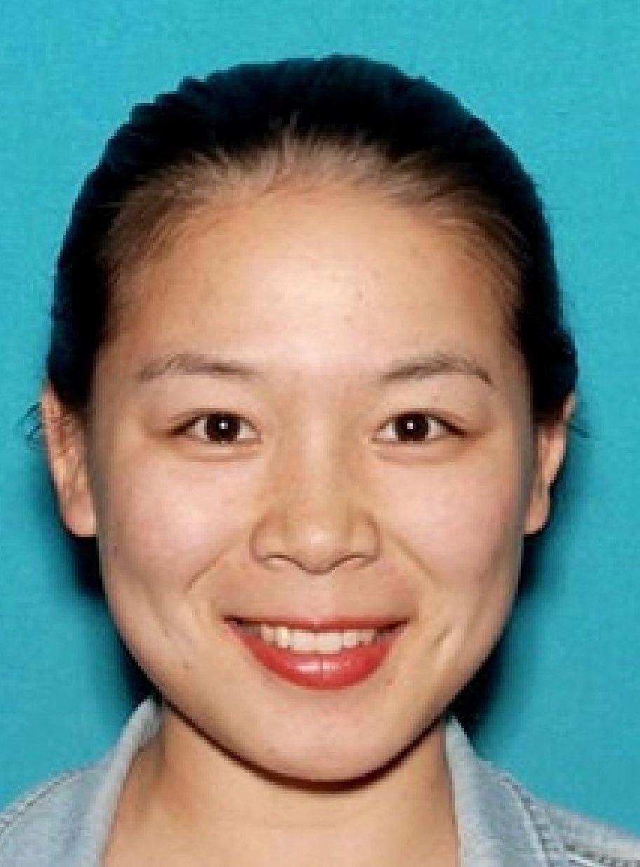 A headshot of a woman with brown eyes and long brown hair tied back, smiling.