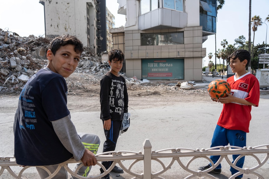 A group of young boys play with a football on a street