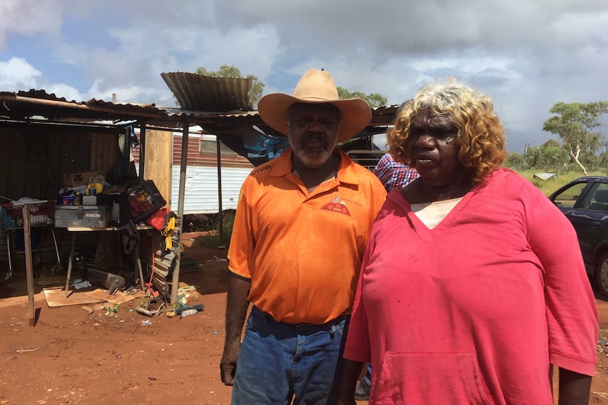 An Aboriginal couple stand outside a shack.