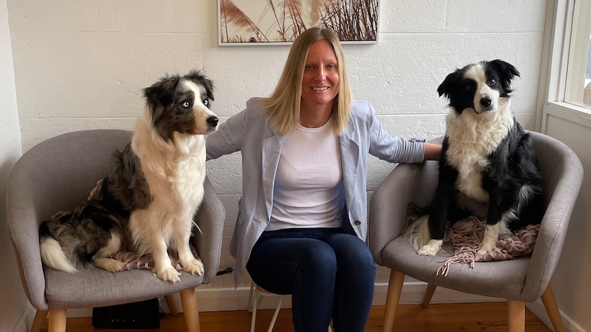 woman sits between two support dogs