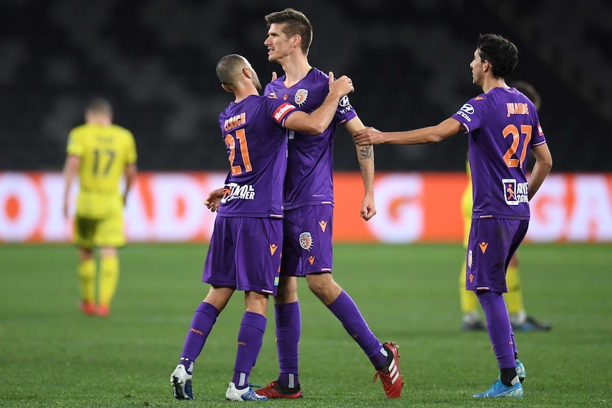 Three Perth Glory A-League players celebrate their elimination final win over Wellington Phoenix.