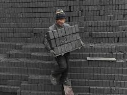 A labourer carries honeycomb briquettes at a coal processing factory in Shenyang, Liaoning province