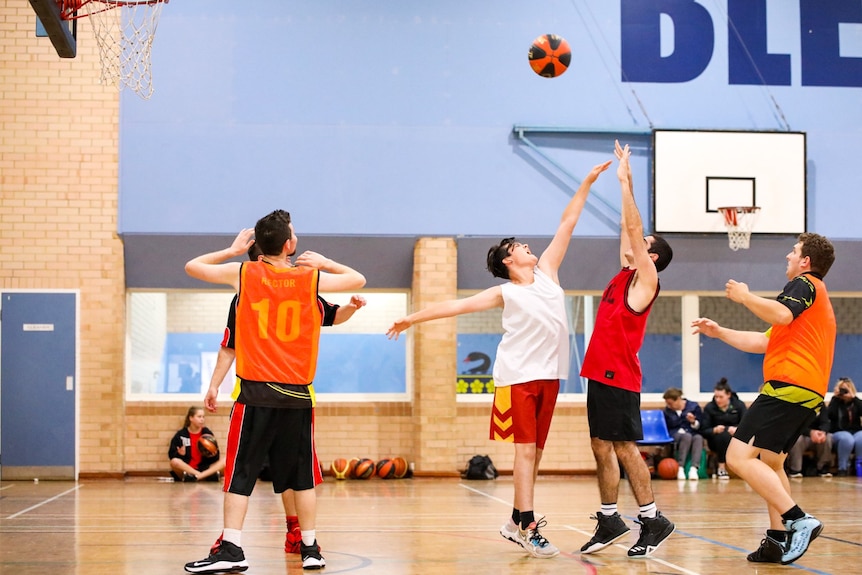 A player on the basketball court tries to block a shot at goal.