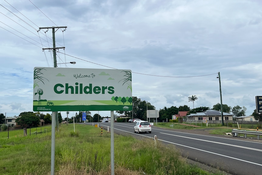 A green sign stands beside a road that says, "Welcome to Childers."